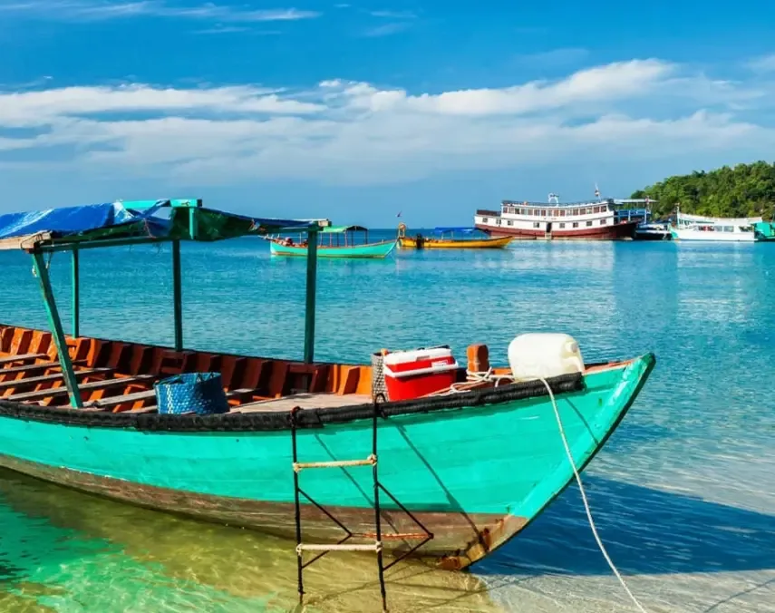 Wooden longtail boats moored in shallow turquoise water off a Cambodian island