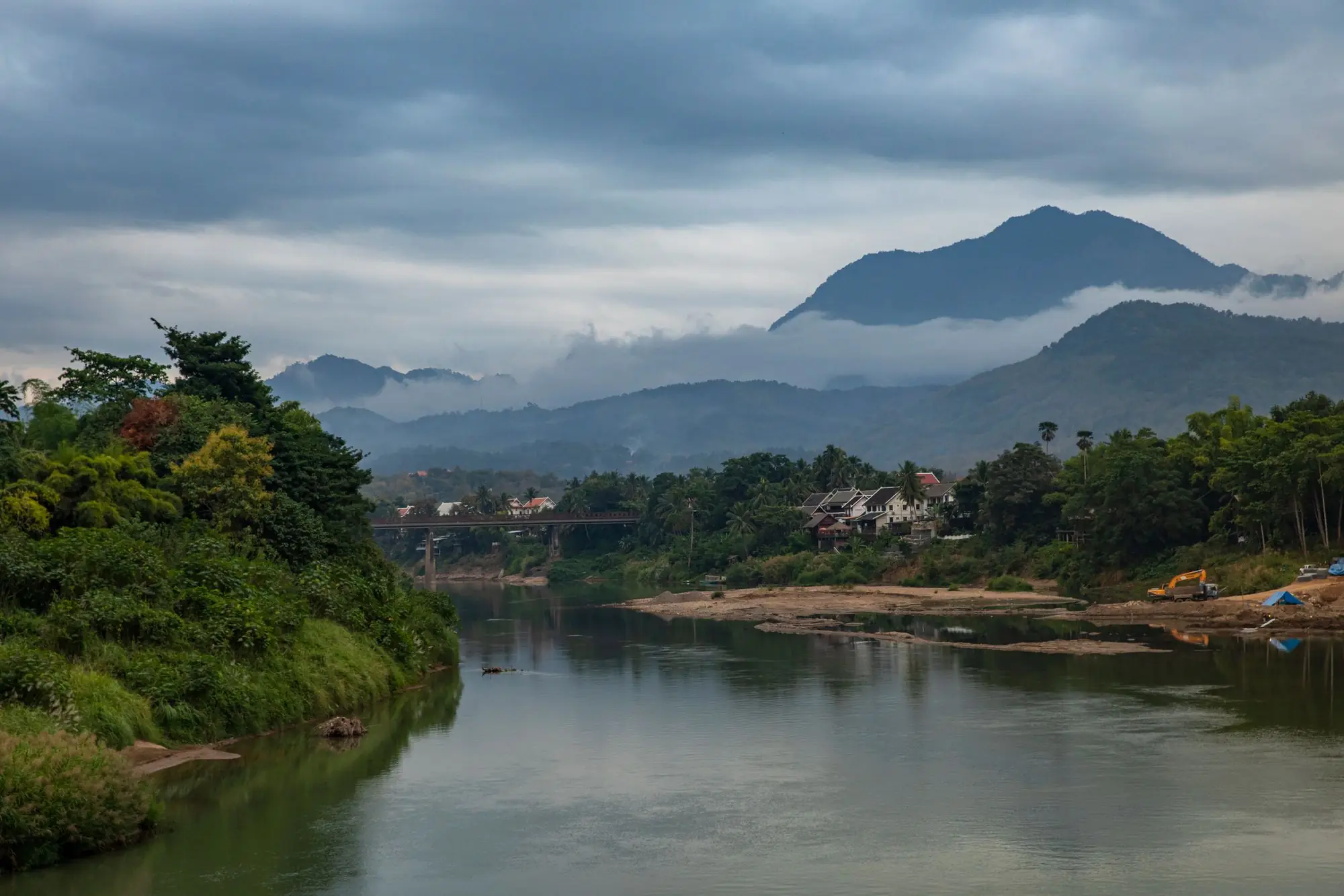 Un río bajo montañas boscosas en Laos, con nubes bajas