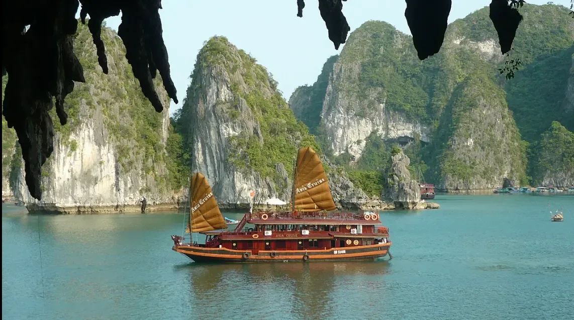 Junco tradicional de velas ocres entre los farallones calizos de la bahía de Ha Long